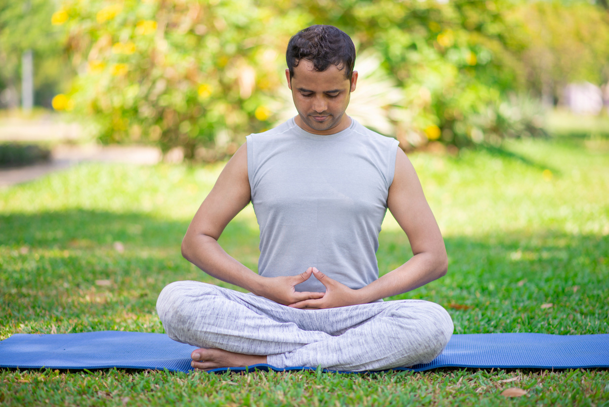 Focused Indian Guy Doing Yoga Asanas in Park